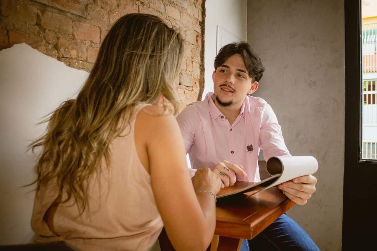 Two adults engaged in a friendly discussion over documents in a cozy café setting.