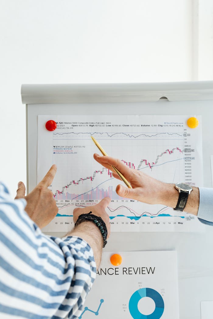 Two people analyzing financial charts on a whiteboard during a business meeting.